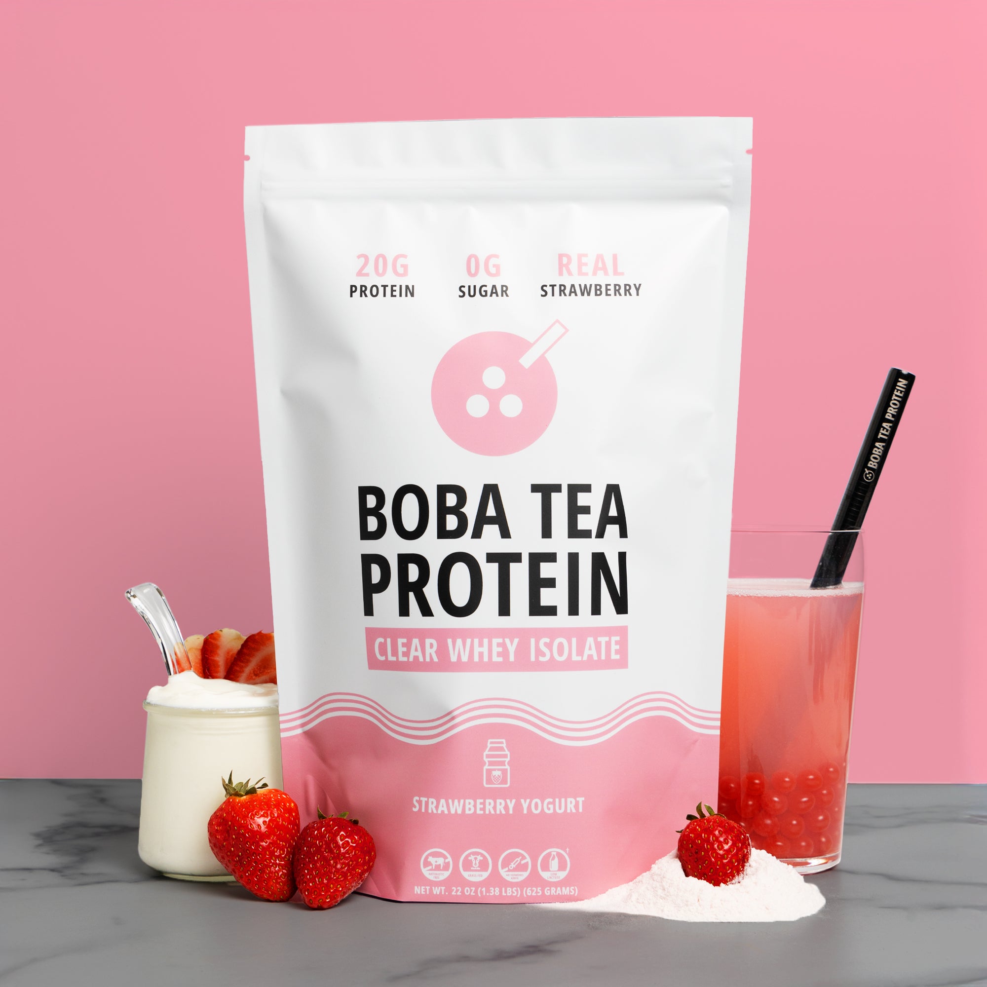 Bag of Boba Tea Protein with a glass of strawberry yogurt drink, and strawberries and yogurt, on a pink background