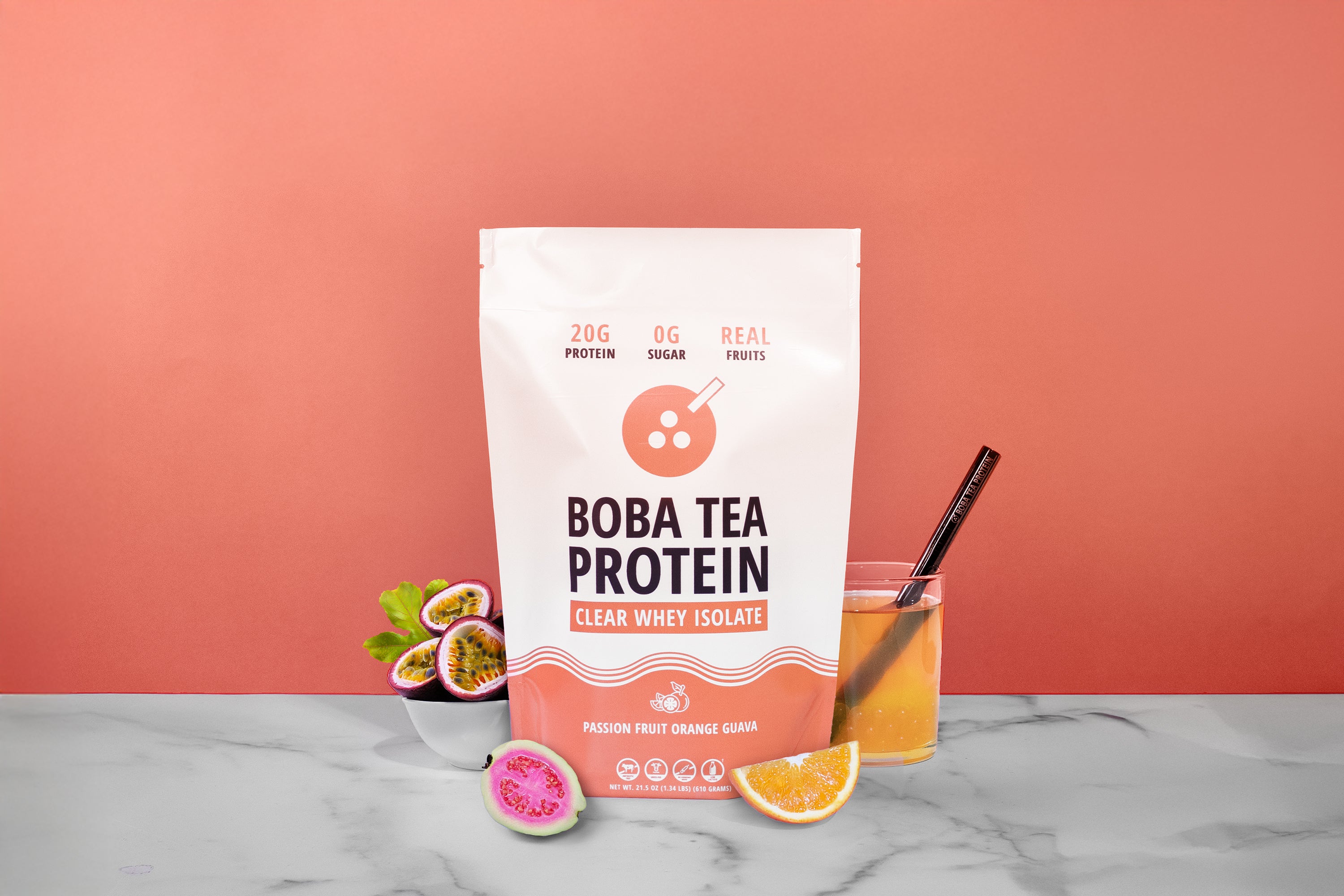 Boba Tea Protein package with a glass of juice and fruit on a marble surface against a pink background