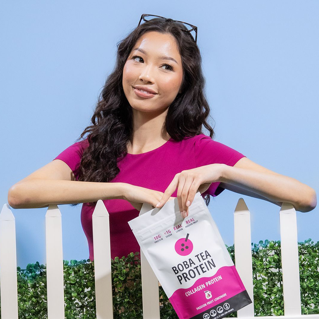 Woman holding a Boba Tea Protein package against a clear blue background