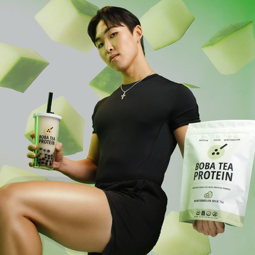 Person holding Boba Tea Protein packaging and a drink with a green background