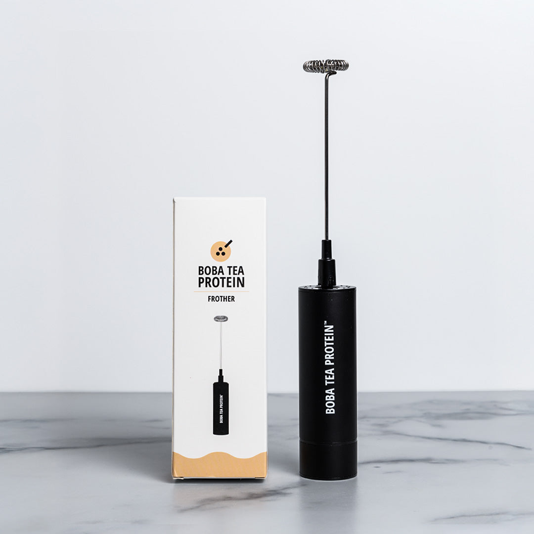 Black milk frother with Boba Tea Protein branding next to its packaging on a marble surface.