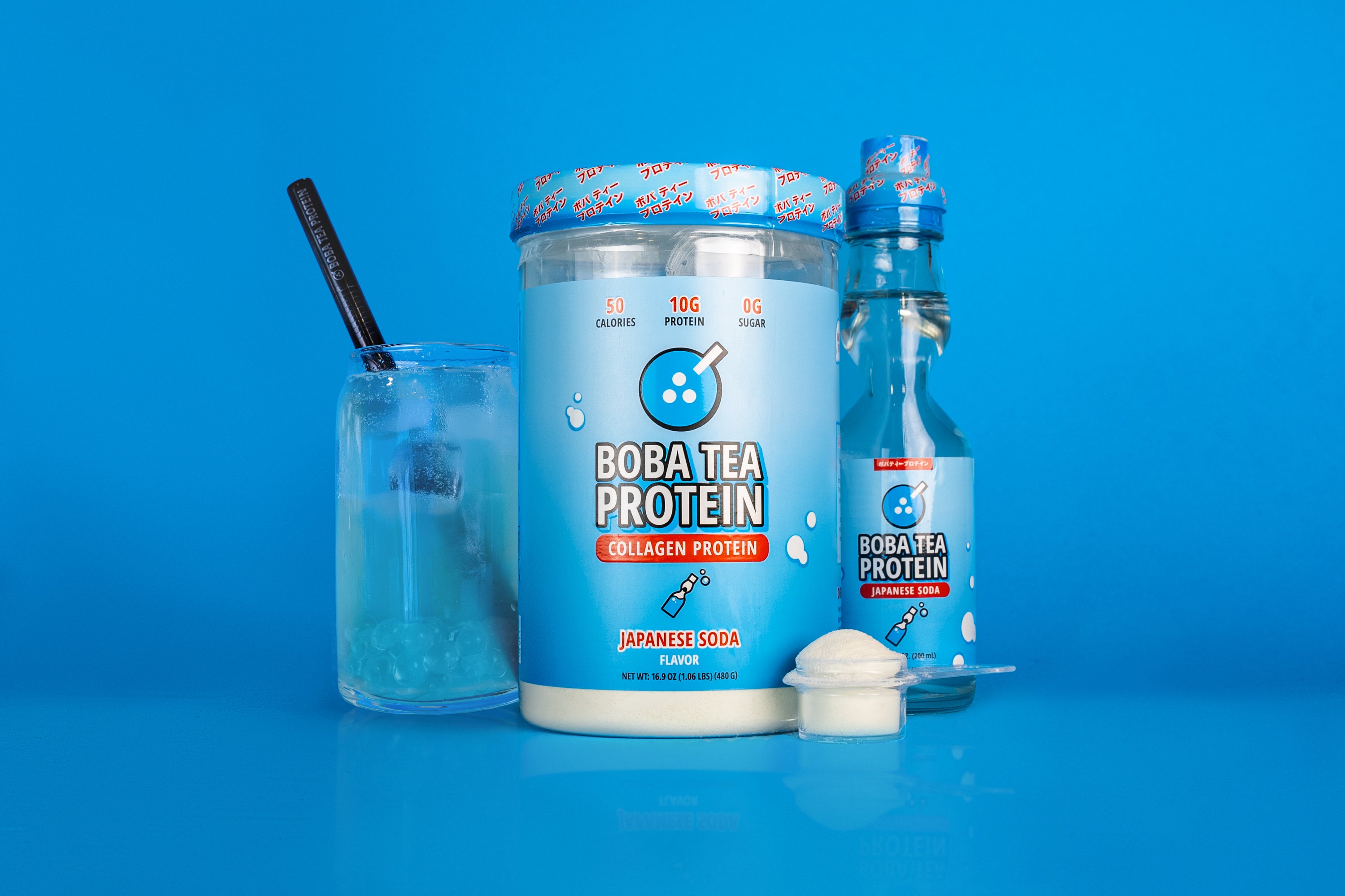A container of "Boba Tea Protein Collagen Protein" in Japanese soda flavor is displayed, with blue packaging showing nutritional details like "50 calories," "10g protein," and "0g sugar." Next to it are a matching glass bottle, a glass of the prepared drink with ice and a black straw, and a small clear scoop of white powder, all set against a vibrant blue background.