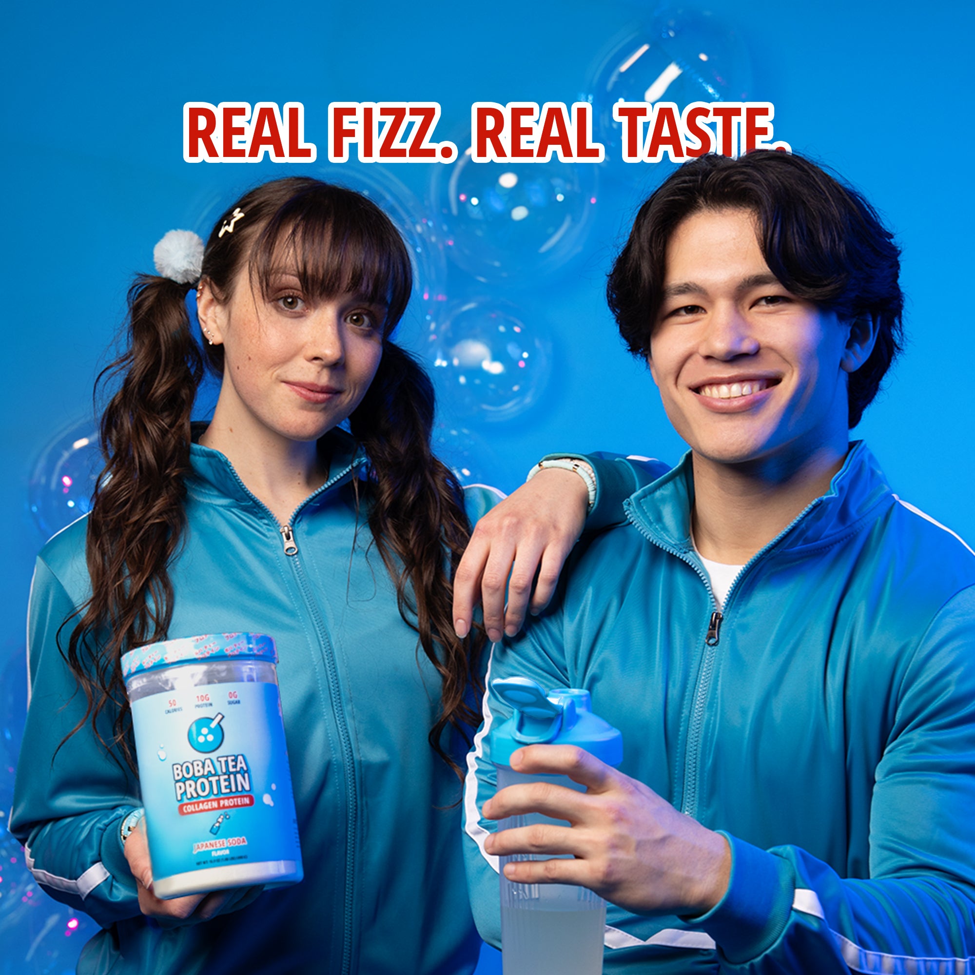 A woman and a man in blue tracksuits hold a container and shaker bottle filled with "Boba Tea Protein Collagen Protein" in Japanese Soda Flavor, with the text "Real Fizz. Real Taste."
