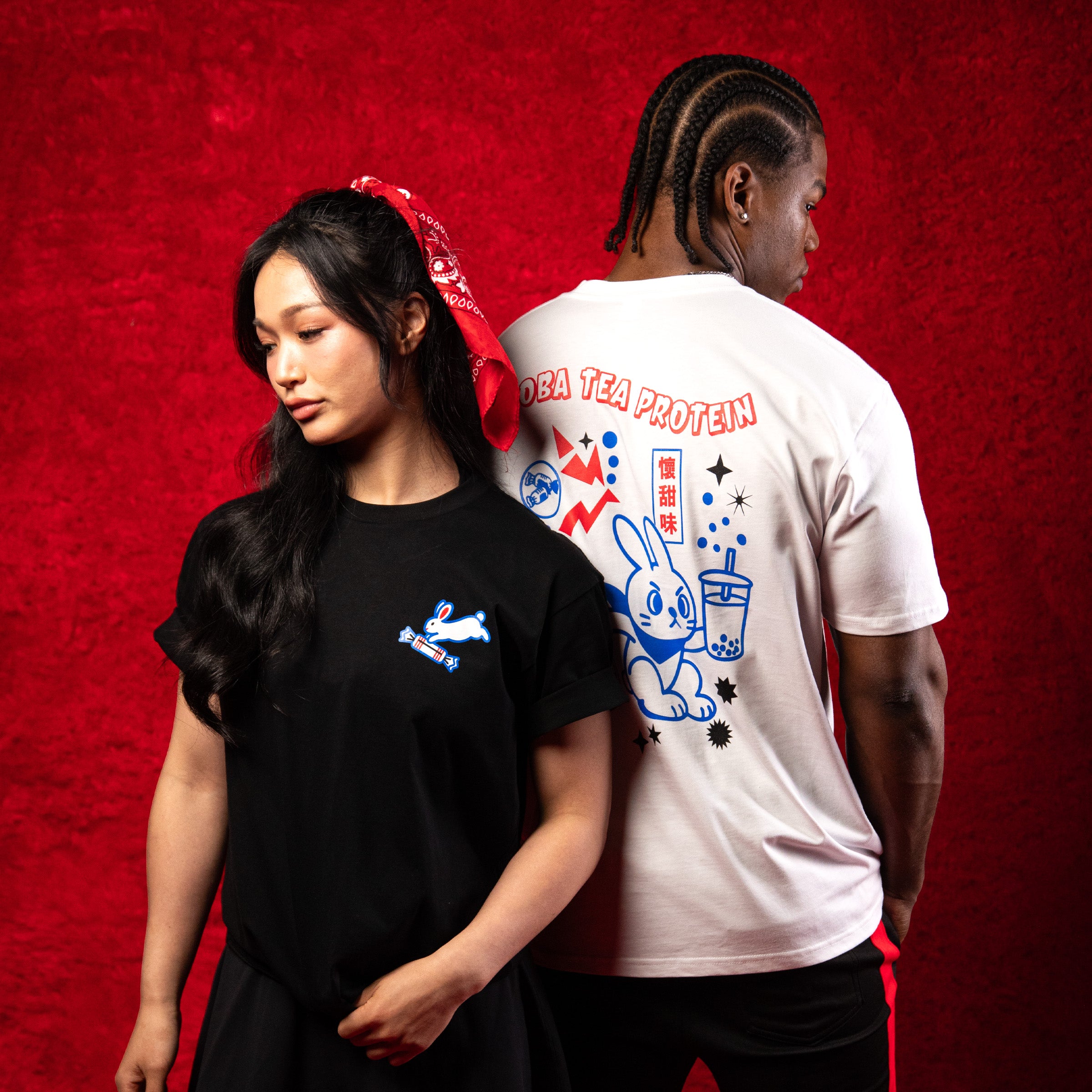 Two people wearing branded t-shirts against a red background