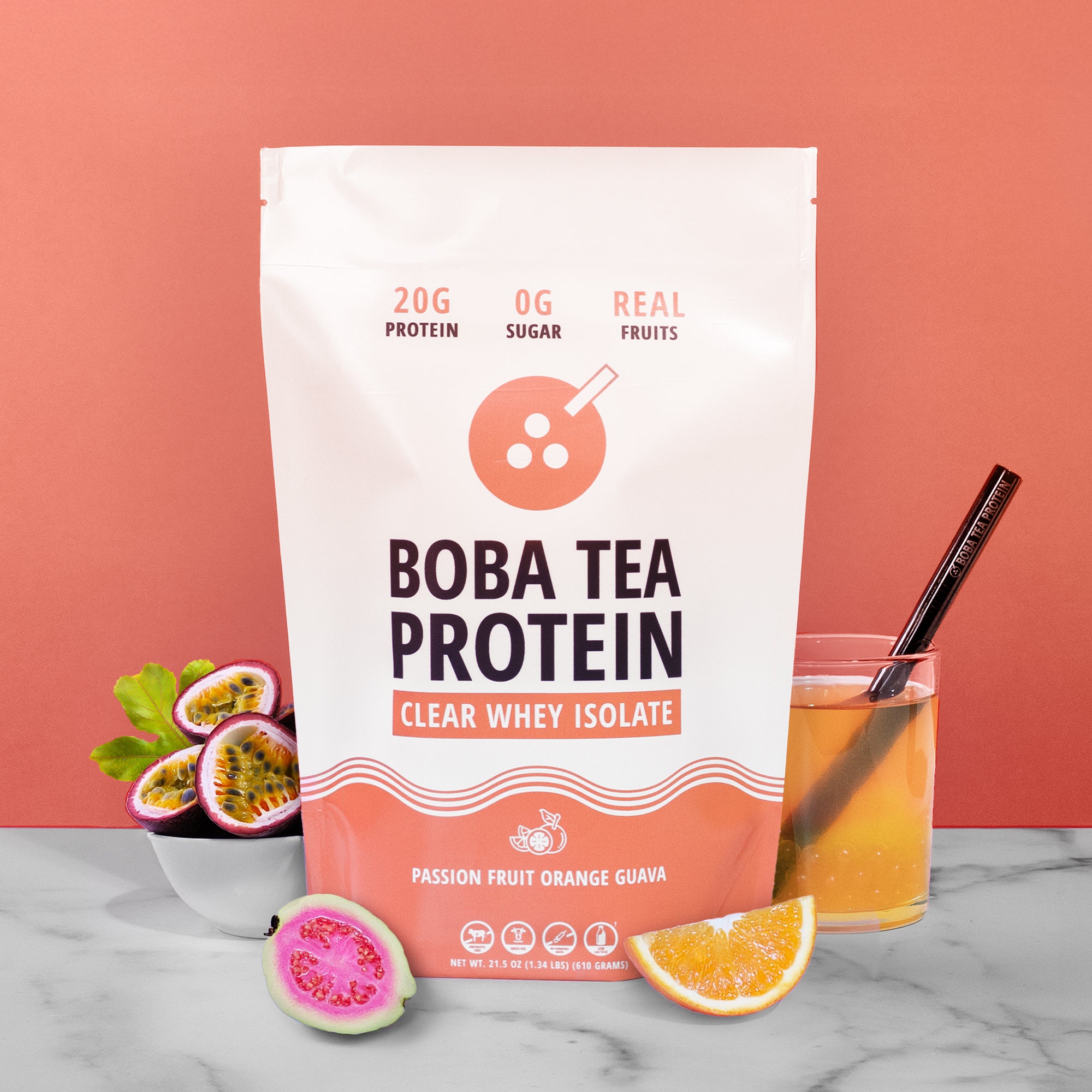 Boba Tea Protein package with a glass of juice and fruit on a marble surface against a pink background
