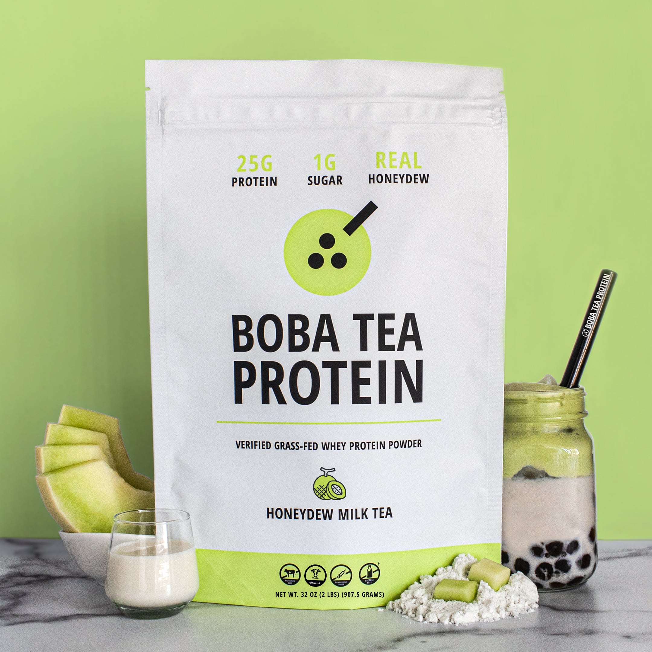 The image shows a bag of "Boba Tea Protein" powder in honeydew flavor, featuring highlights like "25g Protein" and "1g Sugar", against a background of bright light green matching the honeydew theme. In front are fresh honeydew slices, a glass of milk, a scoop of powder, and a jar of milk tea with tapioca pearls and a metal straw.