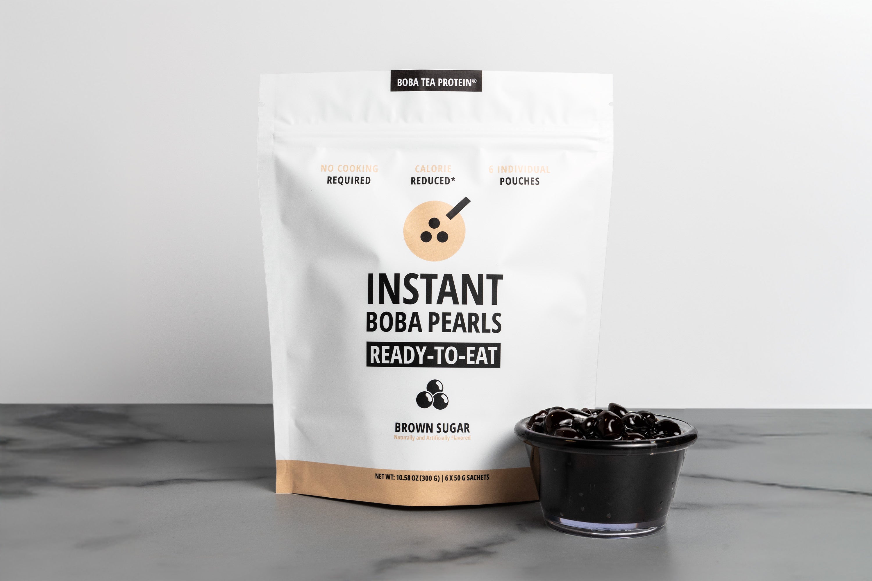 Bag of Instant Boba Pearls with a small bowl of boba pearls on a gray surface.