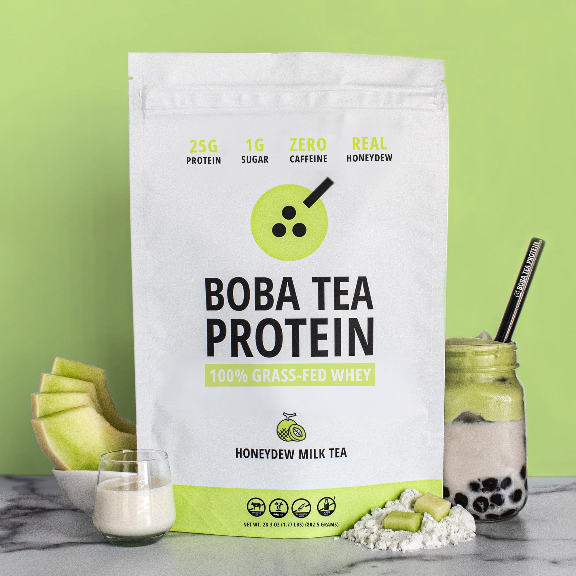 The image shows a bag of "Boba Tea Protein" powder in honeydew flavor, featuring highlights like "25g Protein" and "1g Sugar", against a background of bright light green matching the honeydew theme. In front are fresh honeydew slices, a glass of milk, a scoop of powder, and a jar of milk tea with tapioca pearls and a metal straw.