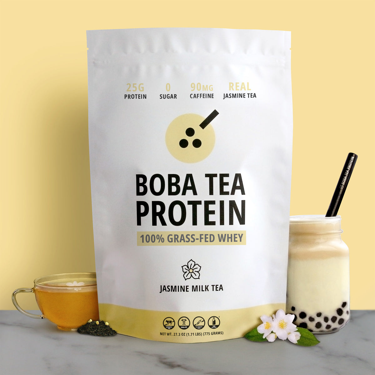A stand-up pouch of Boba Tea Protein powder stands on a marble surface against a pale yellow background. The package is white with black text and a pale yellow graphic, labeled 'BOBA TEA PROTEIN' and 'Jasmine Milk Tea'.
